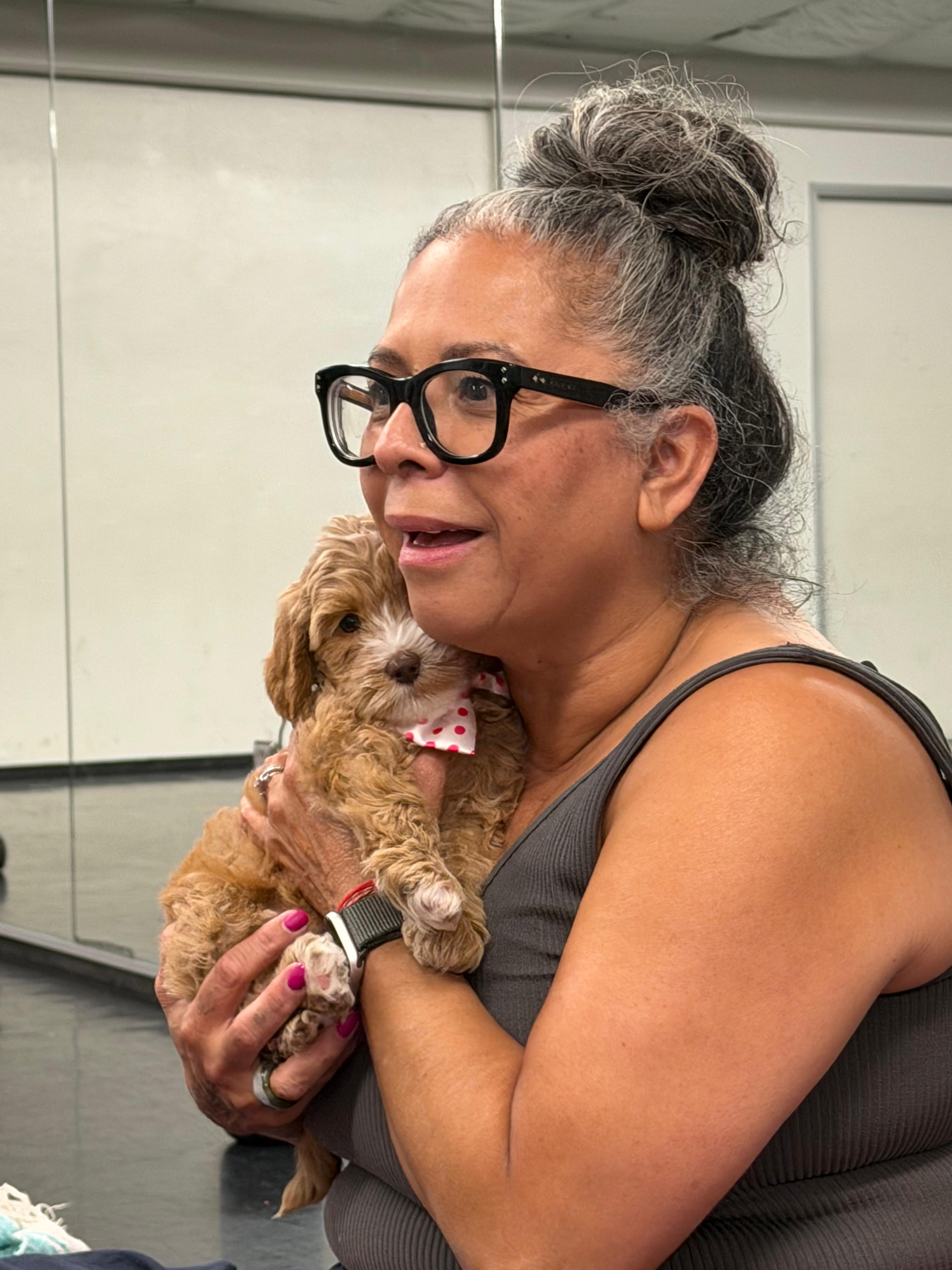 Community visit — a senior resident holding a Doodle puppy